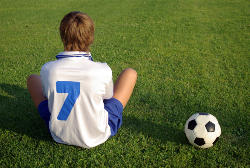 boy sitting on soccor field with ball